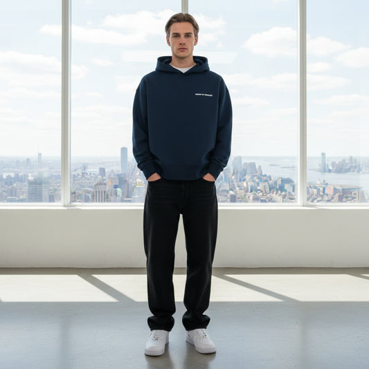Navy blue hoodie with white chest logo on male model in white studio