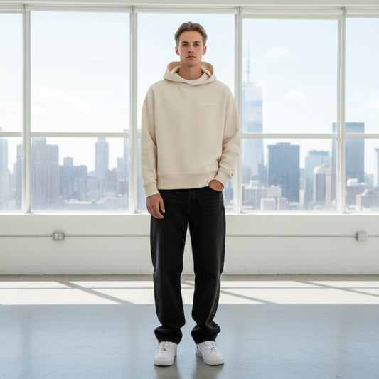 Beige hoodie with white chest logo on male model in white studio