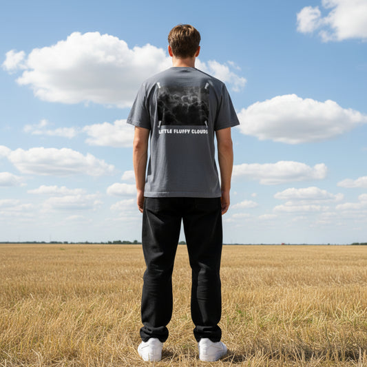 Gray t-shirt with a graphic of clouds and 'Little Fluffy Clouds' text on the back on male model on a field