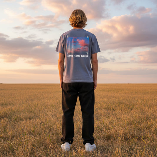 Blue t-shirt with a graphic of clouds and 'Little Fluffy Clouds' text on male model in a field