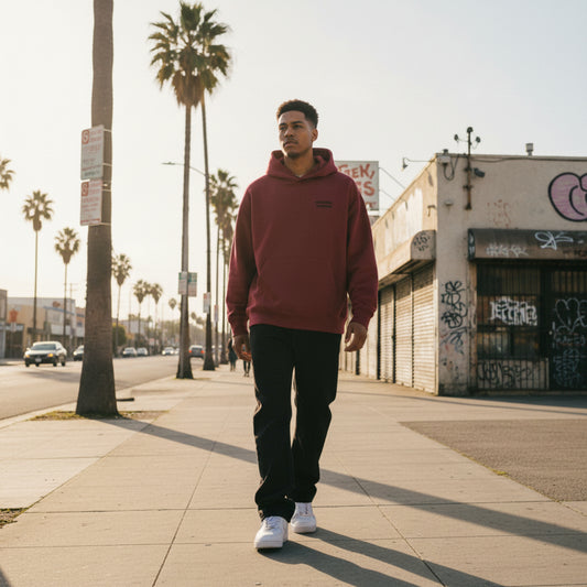 Burgundy hoodie with a small logo on the chest on male model in LA