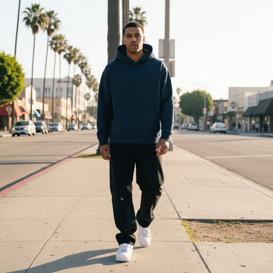 Navy blue hoodie with a small logo on the chest on male model in LA