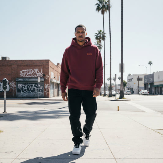 burgundy hoodie with a small brick red text on chest on male model in LA