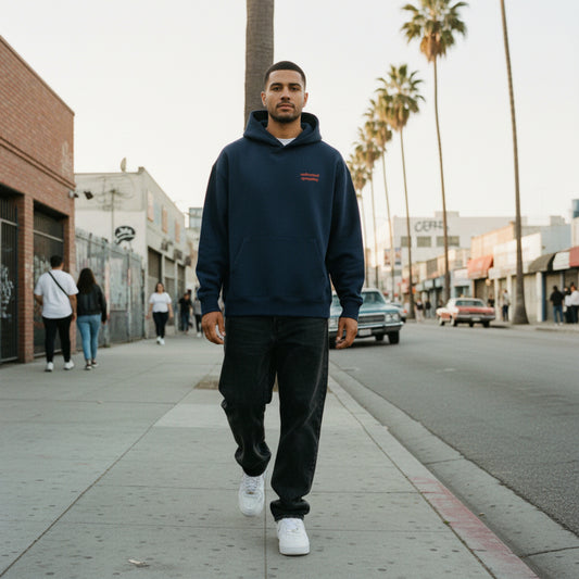 Navy blue hoodie with a small red text on chest on male model in LA